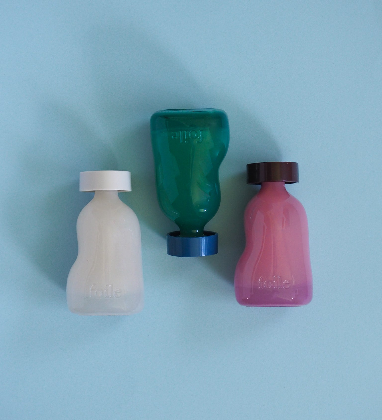 Three bottles of different colors on a light blue background